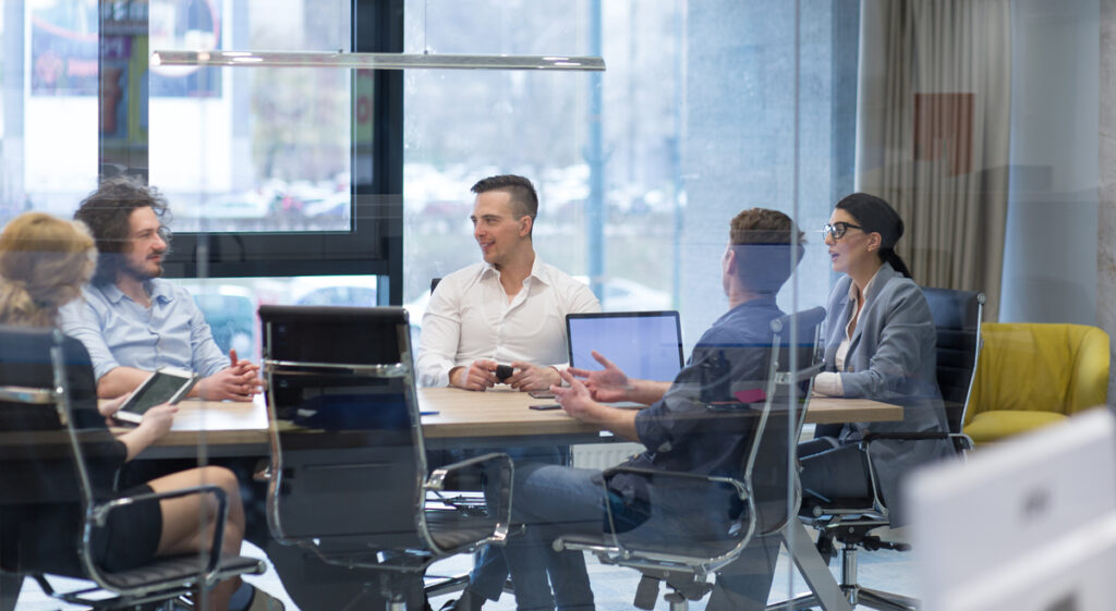 Group of a young business people discussing business plan at modern startup office building (c) AdobeStock