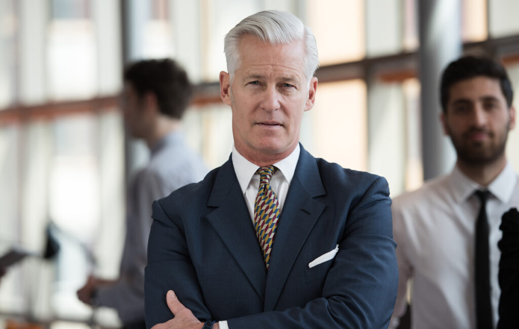 portrait of handsome senior business man with grey hait at modern bright office interior (c) AdobeStock