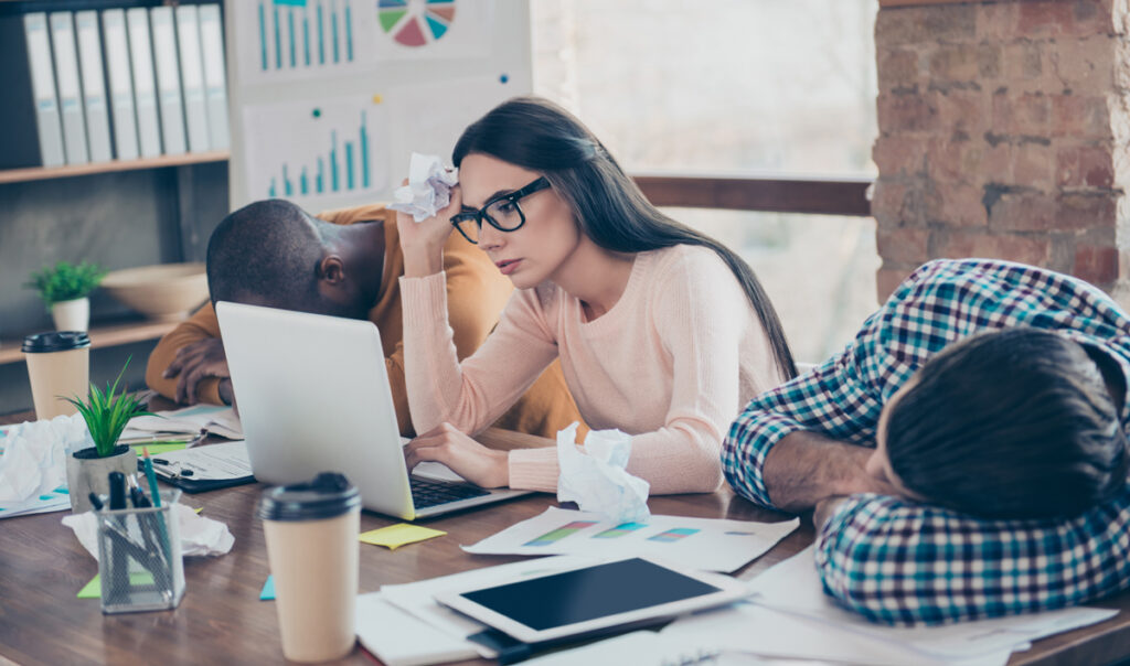 Teilzeitarbeit – so schaut´s aus 1 Eine Frau vor ihrem Laptop, neben ihr schlafen Kollegen auf den Schreibtisch, Stichwort Teilzeit.
(c) AdobeStock