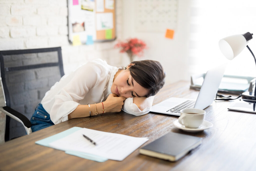 Tired young latin woman sleeping on desk after long hours work on laptop computer. (c) AdobeStock