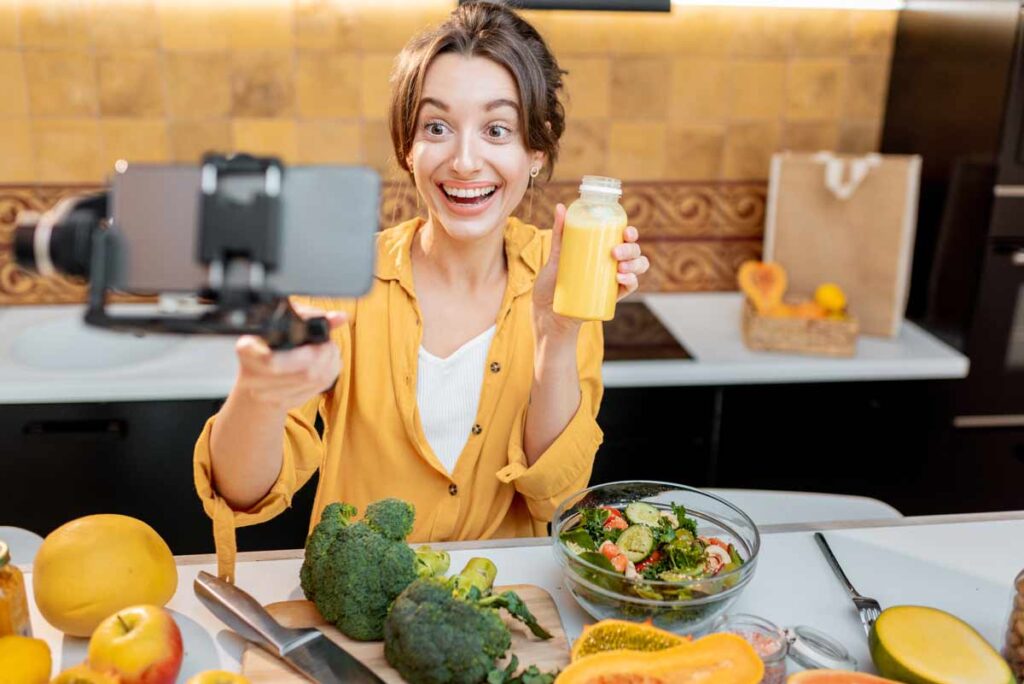 Influencer, Defluencer & Co. war gestern – jetzt kommen die »Introducer«! Influencerin mit Selfiestick beim gesund Kochen. (c) AdobeStock