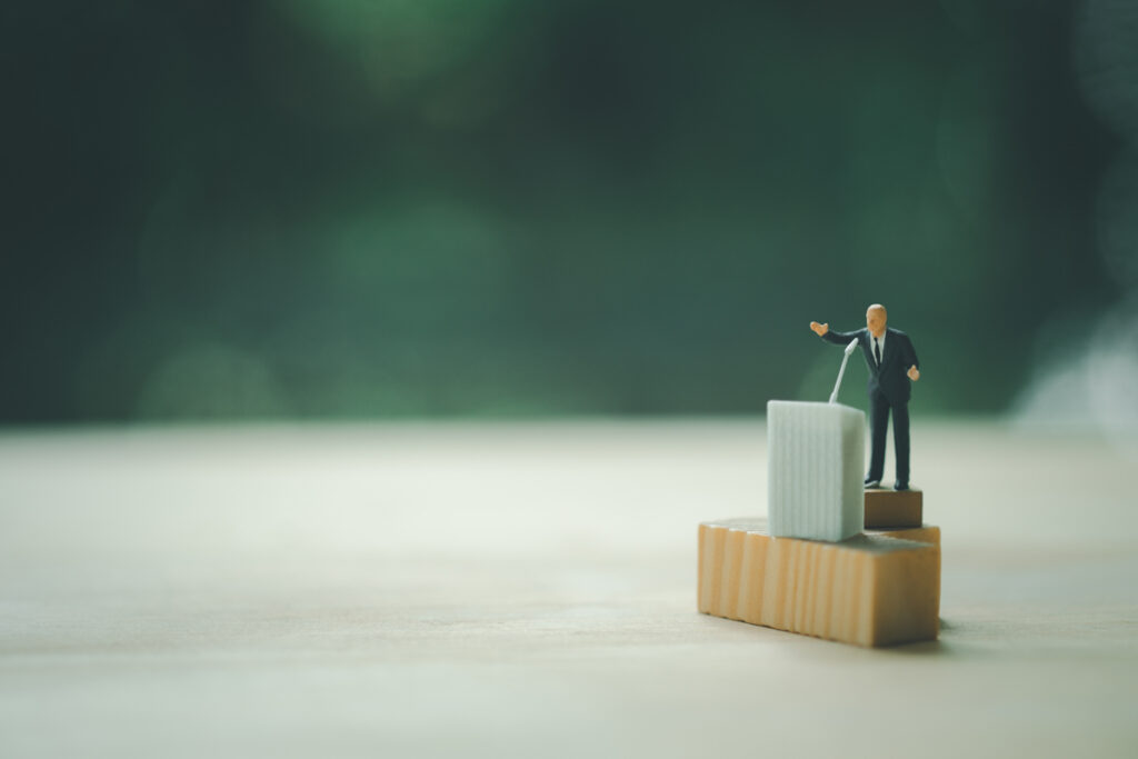 Miniature people of a politician speaking to his crowd. Concept of election (c) AdobeStock