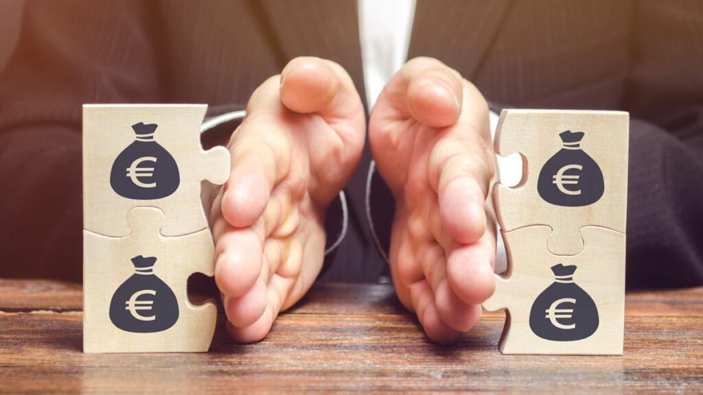 Businessman separates the wooden puzzle with a picture of money. The concept of financial management and distribution of funds. Saving and investing. Property division. Divorce and legal services (c) AdobeStock