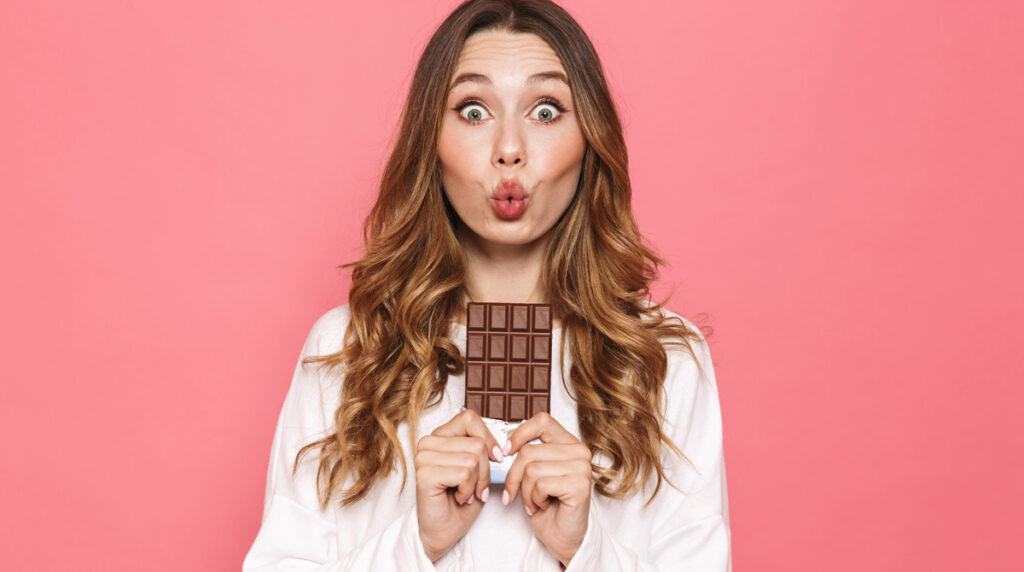 Studie zeigt: Schokoladenkonsum hängt mit unerklärlichen Superkräften zusammen! 1 Portrait of a lovely young woman holding chocolate bar isolated over pink background, Stichwort Schokolade.
(c) AdobeStock