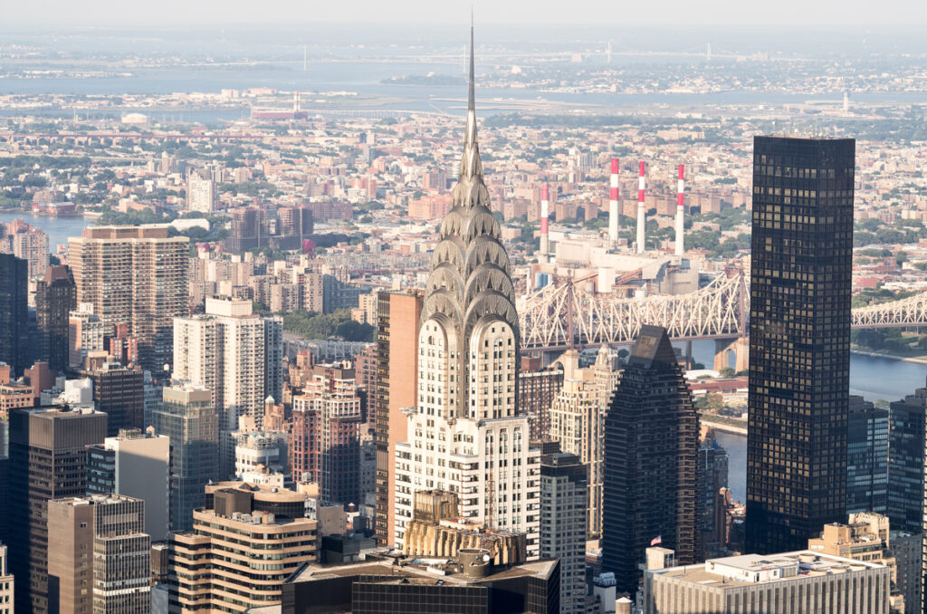 RB: "So komme ich unter die Top 10 der reichsten Menschen der Welt!" 1 Skyscrapers at midtown New York City with the East River on the background.
(c) AdobeStock