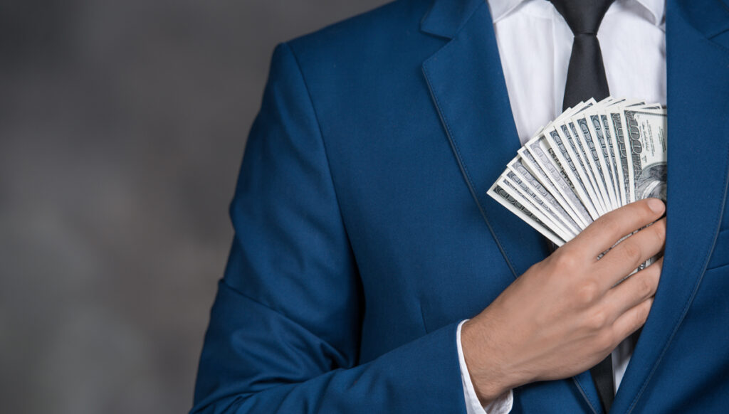 Male person putting money banknotes into pocket finance corruption (c) AdobeStock
