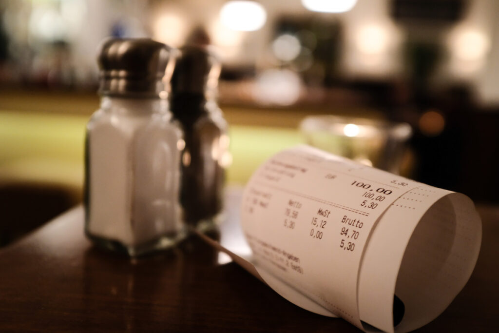 Neuer Gastro-Trend mit Tellergebühr, Servierzuschlag, Bröselsteuer u.v.m. 2 Eine Rechnung neben einem Salz- und Pfefferstreuer, Stichwort Tellergebühr.
(c) AdobeStock