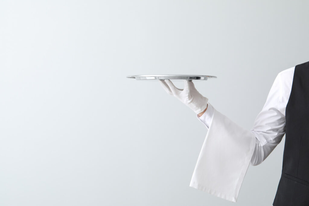 Handsome waiter with empty tray on light background. (c) AdobeStock