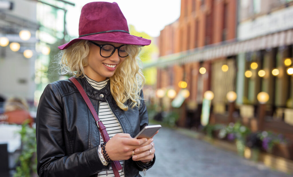 Eine Frau, die auf ihrem iPhone tippt. (c) AdobeStock