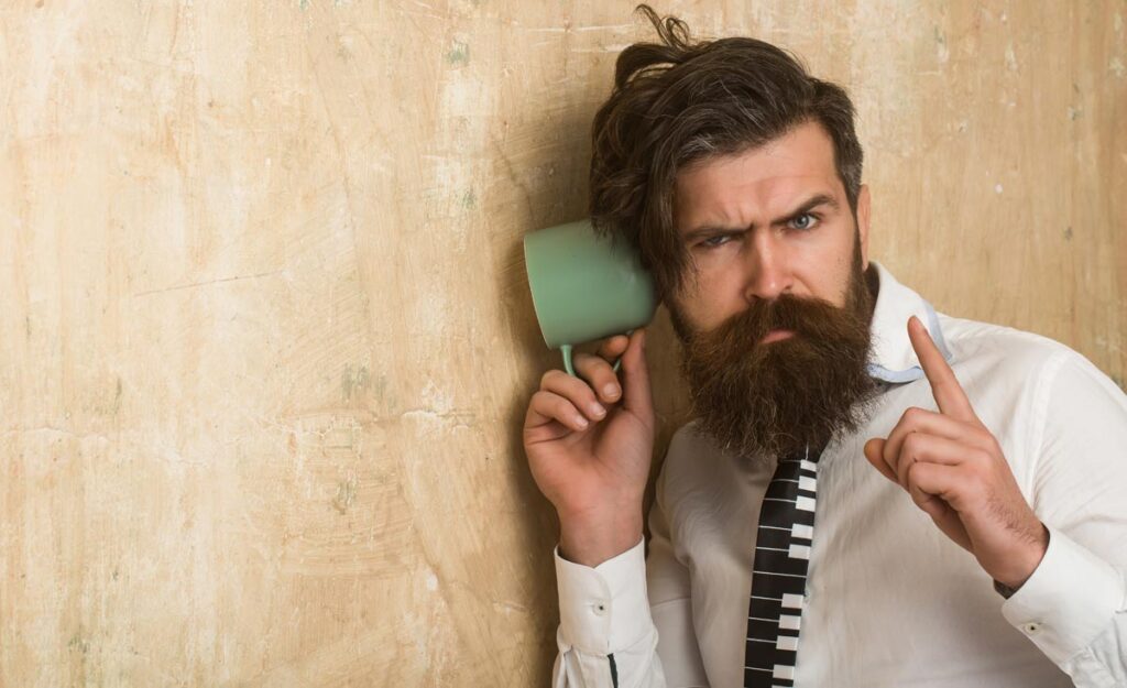 Studie zeigt: Männer tratschen »viel mehr« als Frauen! 1 Ein Mann, der mit Hilfe eines Häferls an einer Wand lauscht, Stichwort tratschen.
(c) AdobeStock