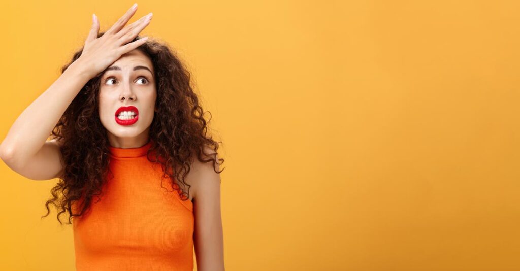 Eine Frau, die sich mit der flachen Hand an die Stirn greift, weil sie etwas vergessen hat. (c) AdobeStock