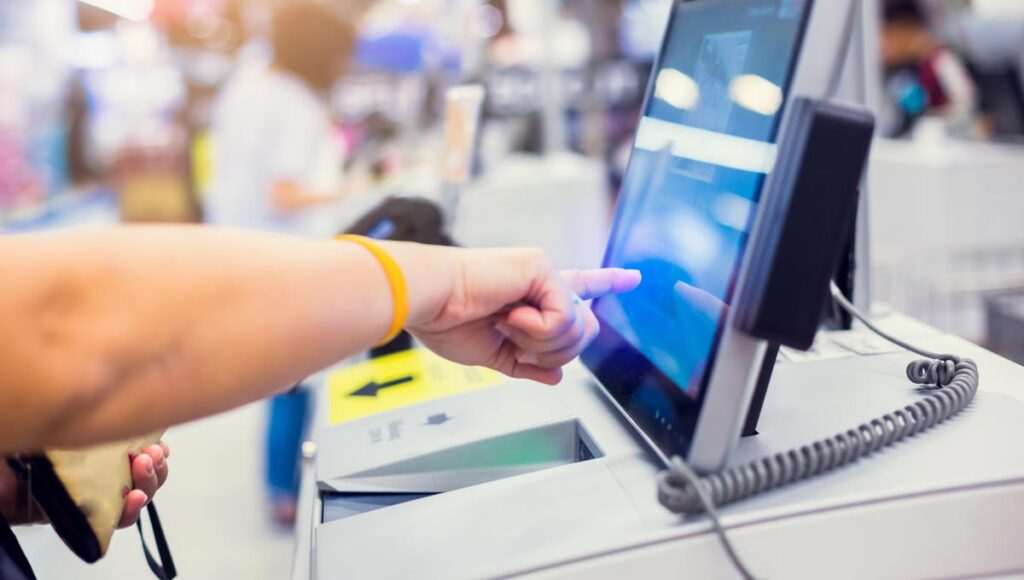 Die Hand einer Frau an einer Selbstbedienungskassa im Supermarkt. (c) AdobeStock