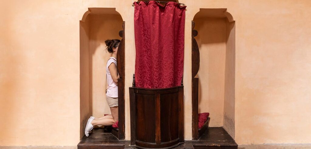 Eine Frau in einem Beichtstuhl. (c) AdobeStock