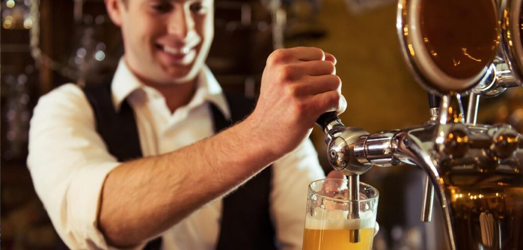 Ein Mann beim Zapfen eines Biers. (c) AdobeStock