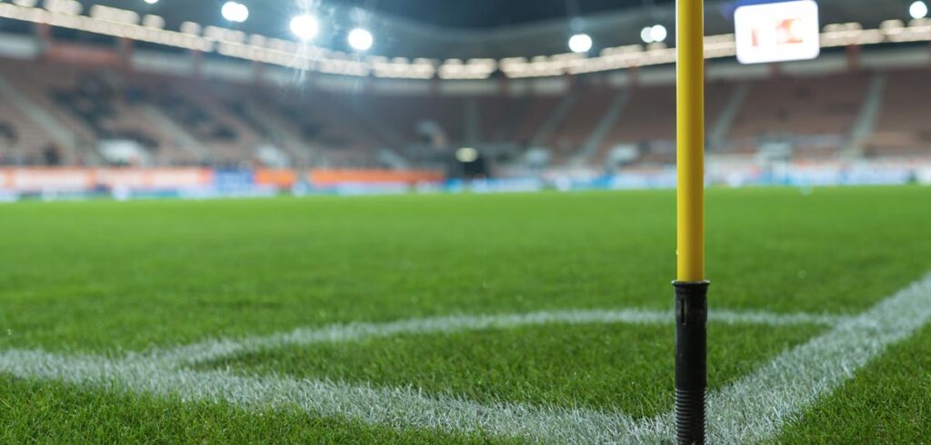Close-Up: ein Fußballstadion von der Cornerfahne aus fotografiert. (c) AdobeStock
