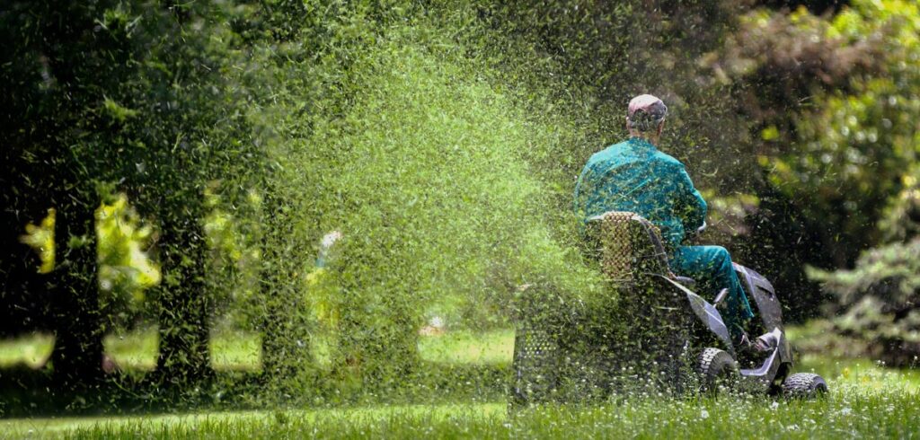 Ein Mann mit einem Rasenmähertraktor. (c) AdobeStock