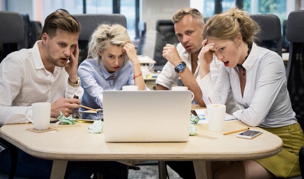8 Fehler, die man beim Fehlermachen vermeiden sollte 1 Zwei Frauen und zwei Männer vor einem Laptop an einem Schreibtisch, Stichwort Fehlermachen.
(c) AdobeStock