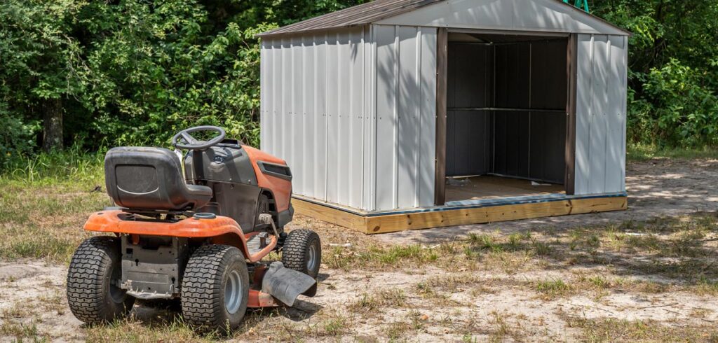 Ein Rasenmäher Traktor vor einem offenen Geräteschuppen. (c) AdobeStock