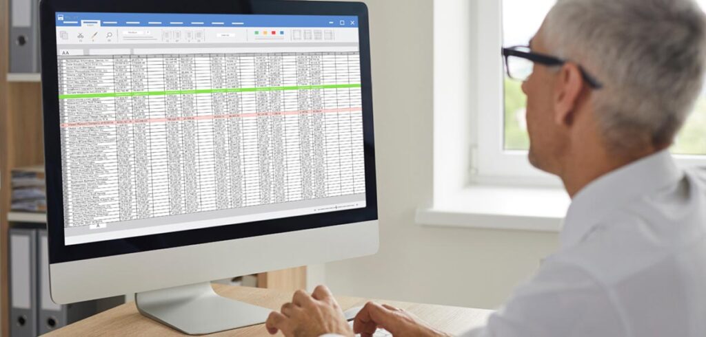 Ein Mann vor einem Monitor beim Bearbeiten einer Excel-Tabelle. (c) AdobeStock
