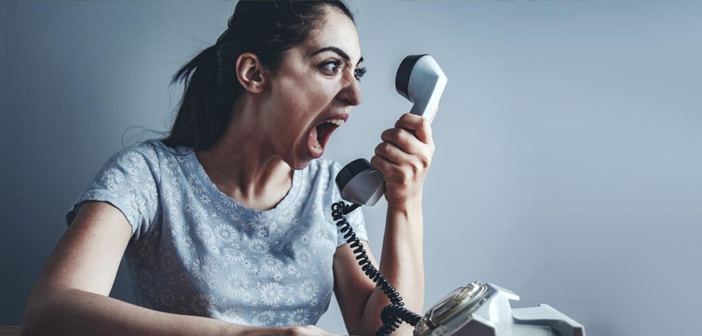 Studie: Menschen reagieren empfindlicher auf Kritik, wenn sie kritisiert werden Eine Frau, die wütend in einen Telefonhörer schreit. (c) AdobeStock
