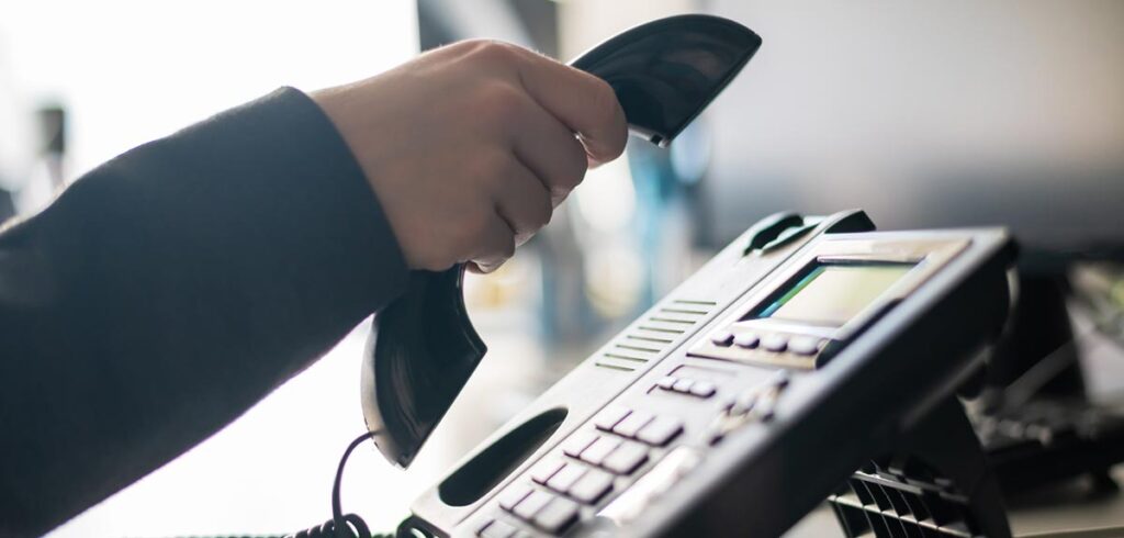 Die Hand eines Mannes, der eine Telefonhörer abhebt. (c) AdobeStock