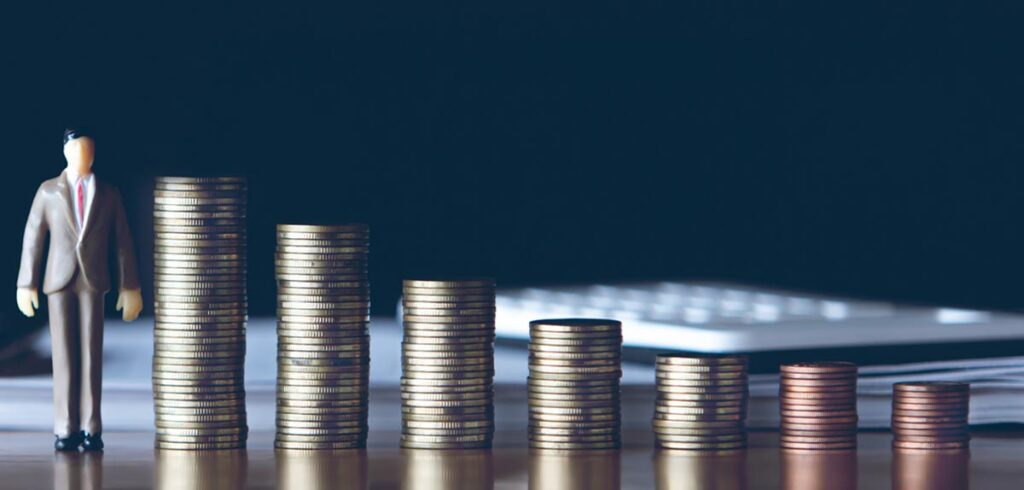 Illustration: Ein Mann im Anzug neben Stapel von Münzen, die immer kleiner werden. (c) AdobeStock
