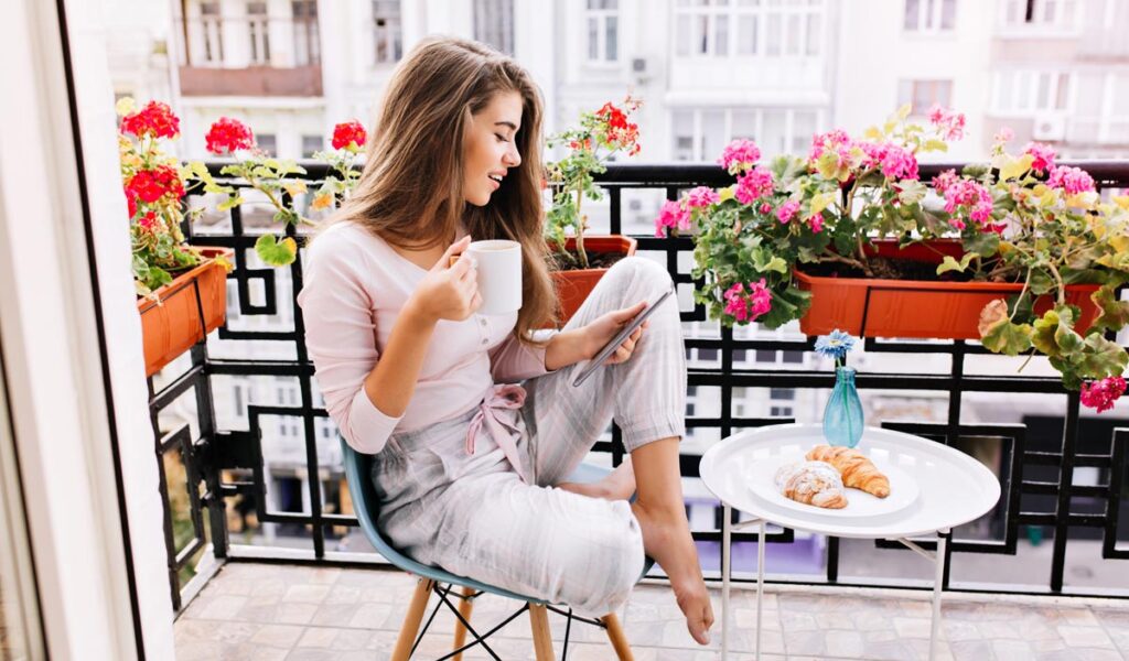 Balkonien ist auch schon zu überlaufen – die neuesten Trends für den Sommer 2025ff 1 Eine Frau sitzt auf einem Balkon mit dem Handy in der einen und einem Kaffeehäferl in der anderen Hand, vor ihr ein Tischchen mit Kroissants, Stichwort Balkonien.
(c) AdobeStock